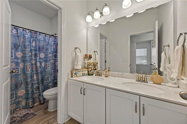 full bathroom featuring wood finished floors, toilet, double vanity, and curtained shower