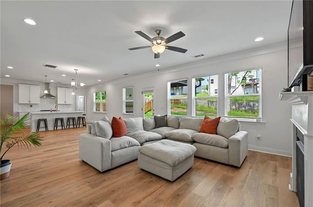 living room with recessed lighting, healthy amount of natural light, ornamental molding, a fireplace, and ceiling fan