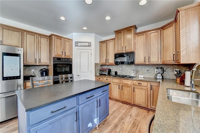 kitchen featuring a center island, black appliances, sink, light hardwood / wood-style flooring, and decorative backsplash