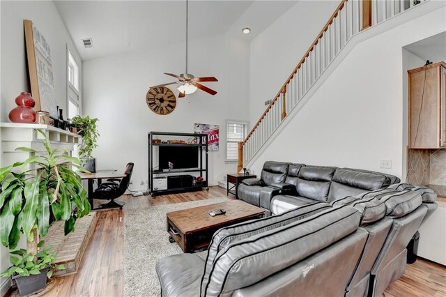 living room featuring ceiling fan, light hardwood / wood-style floors, and high vaulted ceiling