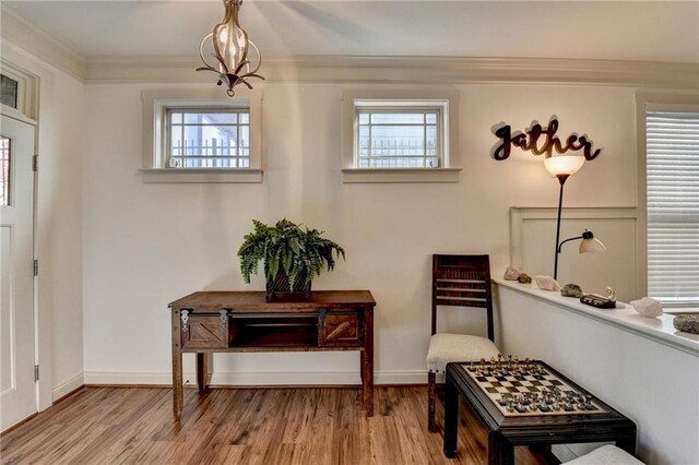 sitting room featuring a notable chandelier, wood-type flooring, ornamental molding, and a wealth of natural light