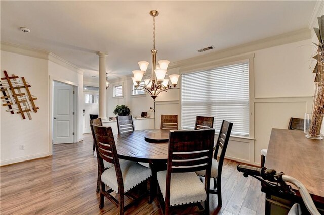 dining room with hardwood / wood-style floors, a healthy amount of sunlight, a notable chandelier, and ornamental molding