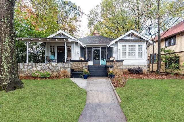 view of front of property with a porch, a chimney, a front lawn, and a shingled roof