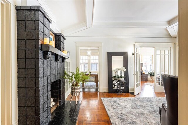 foyer entrance featuring beamed ceiling, baseboards, a brick fireplace, and crown molding