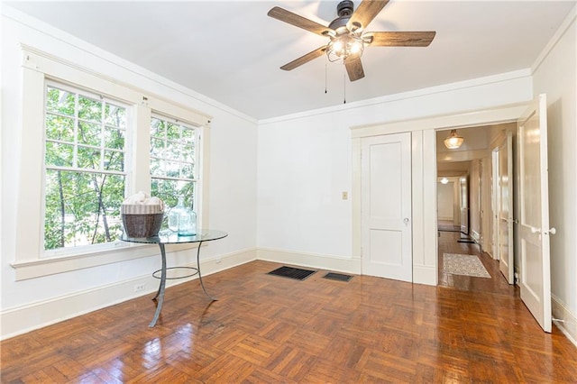 empty room with ceiling fan, visible vents, baseboards, and ornamental molding