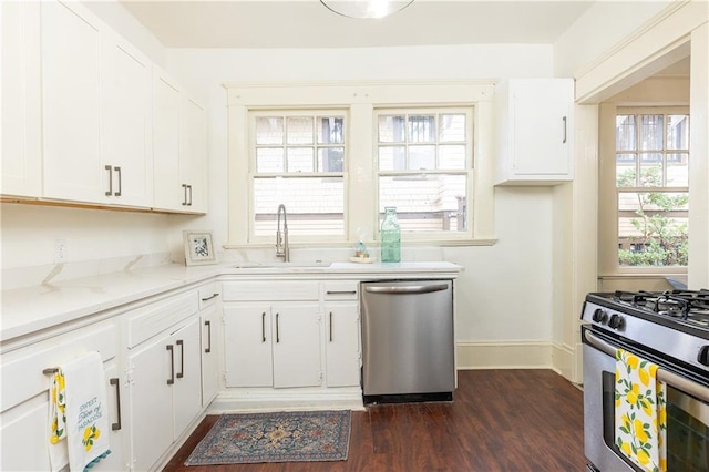 kitchen with dark wood finished floors, white cabinets, appliances with stainless steel finishes, and a sink