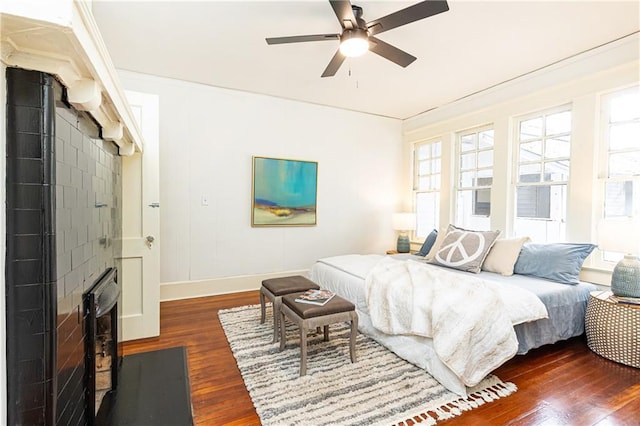 bedroom with crown molding, a ceiling fan, dark wood-type flooring, and baseboards