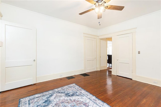 spare room with baseboards, wood finished floors, visible vents, and ornamental molding