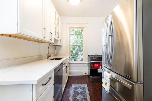 kitchen with dark wood finished floors, light stone counters, appliances with stainless steel finishes, white cabinets, and a sink