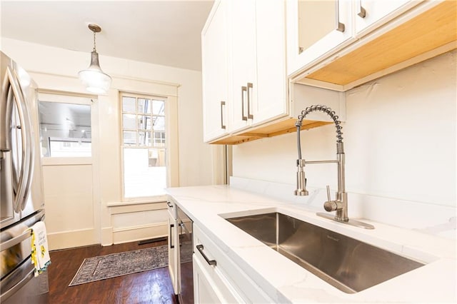 kitchen featuring light stone countertops, pendant lighting, stainless steel appliances, white cabinetry, and a sink