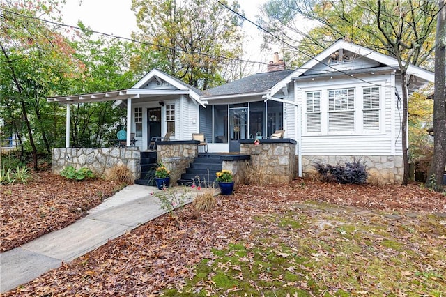 bungalow-style home with covered porch, a chimney, and a sunroom