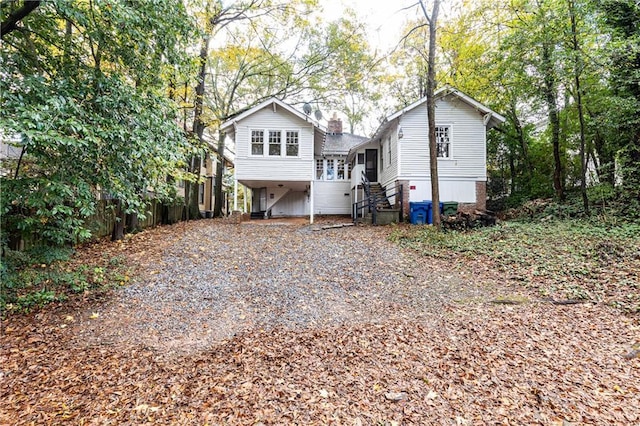 rear view of house with a chimney and gravel driveway