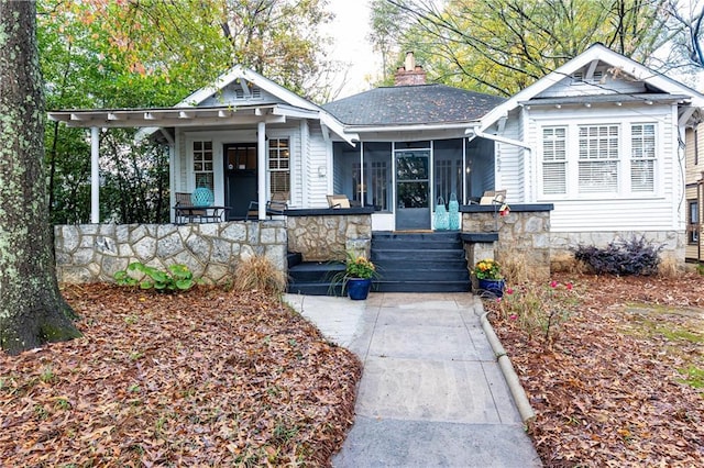 bungalow featuring a porch, a chimney, and a sunroom