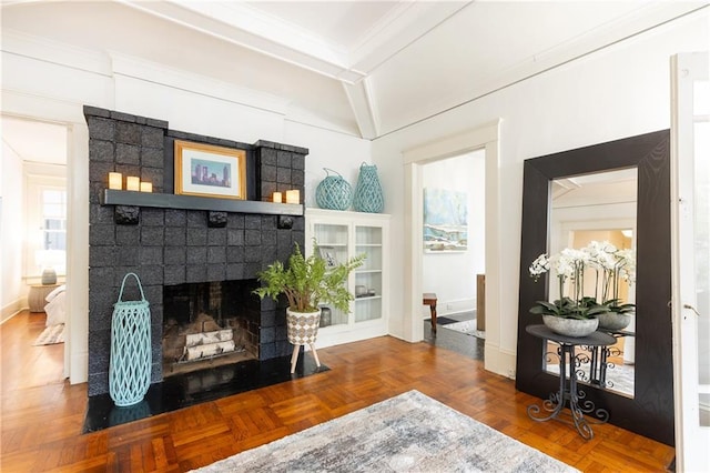 living area featuring a fireplace, crown molding, and baseboards