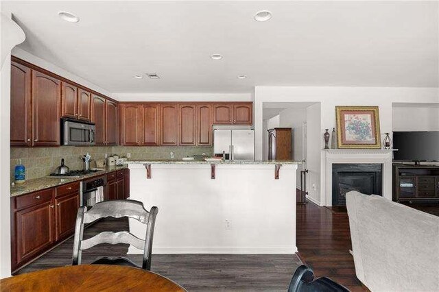 316 Branch Valley Dr NE, Dallas, GA 30132 - kitchen featuring stainless steel appliances, a kitchen bar, light stone counters, dark wood-type flooring, and recessed lighting