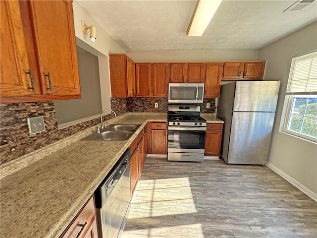 3589 Main Station Dr SW, Marietta, GA 30008 - kitchen featuring light wood-type flooring, stainless steel appliances, sink, backsplash, and a textured ceiling