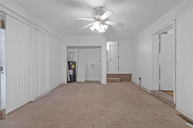 interior space with ceiling fan, light carpet, and water heater