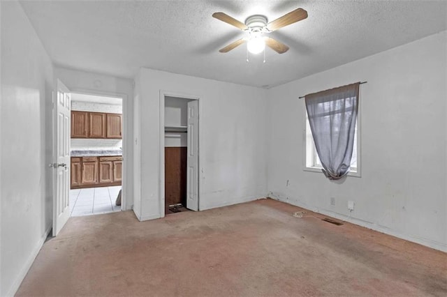 unfurnished bedroom featuring a textured ceiling, light colored carpet, and ceiling fan