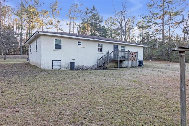 rear view of property featuring a deck, cooling unit, and a lawn