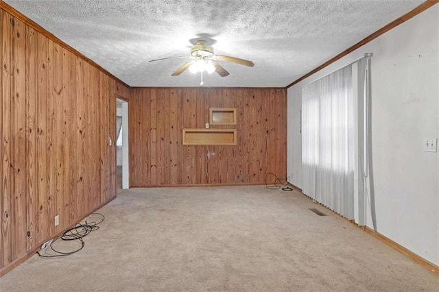 empty room featuring light carpet, a textured ceiling, ceiling fan, and ornamental molding