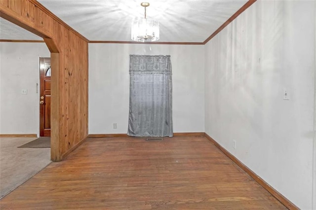 spare room featuring hardwood / wood-style floors, an inviting chandelier, and crown molding