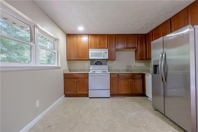 115 Delmoor Dr NW, Atlanta, GA 30311 - kitchen featuring white appliances, brown cabinetry, baseboards, light stone countertops, and a textured ceiling