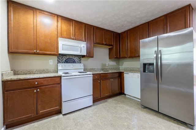 115 Delmoor Dr NW, Atlanta, GA 30311 - kitchen featuring white appliances, light flooring, light stone counters, brown cabinetry, and a textured ceiling