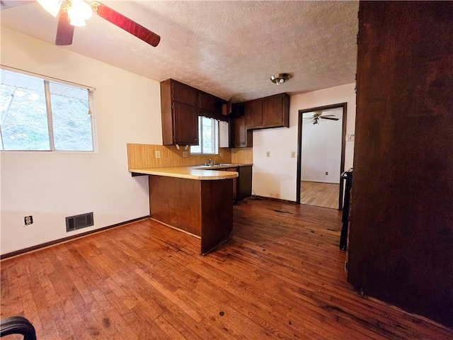 kitchen featuring ceiling fan, wood-type flooring, a textured ceiling, and kitchen peninsula