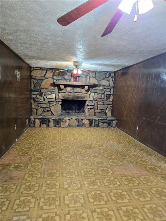 unfurnished living room with light parquet floors, wood walls, a textured ceiling, and a fireplace