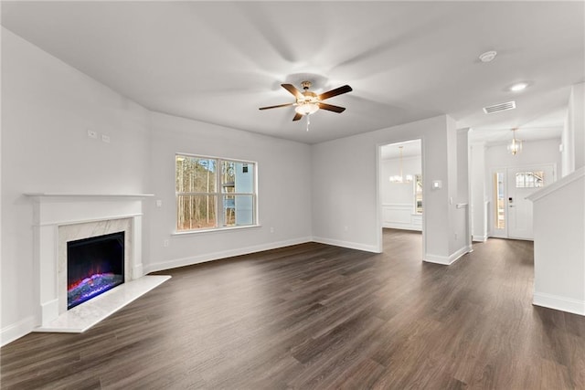 unfurnished living room with a wealth of natural light, a fireplace, visible vents, and ceiling fan with notable chandelier