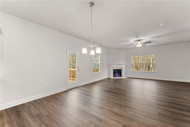unfurnished living room featuring ceiling fan, dark wood-type flooring, and plenty of natural light