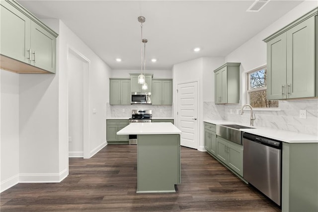 kitchen featuring decorative backsplash, stainless steel appliances, green cabinets, and a sink