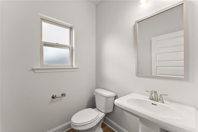 bathroom featuring a sink, toilet, baseboards, and wood finished floors
