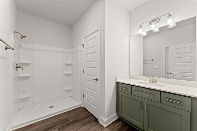 bathroom featuring baseboards, walk in shower, vanity, and wood finished floors