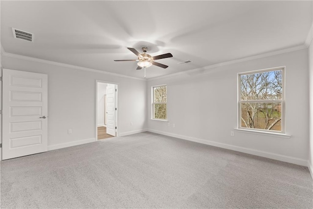 carpeted spare room featuring ornamental molding, baseboards, a ceiling fan, and visible vents