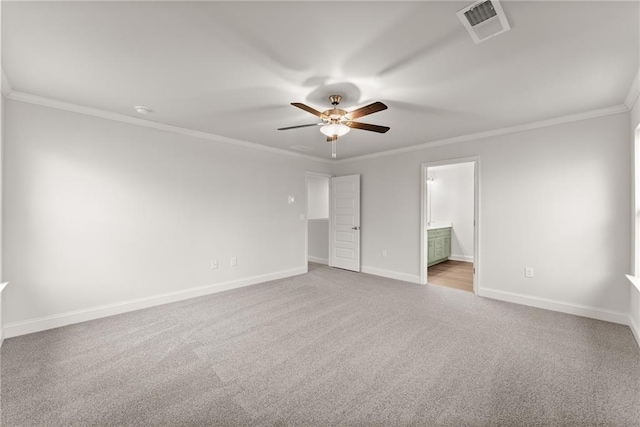 unfurnished bedroom featuring baseboards, ensuite bathroom, visible vents, crown molding, and carpet floors