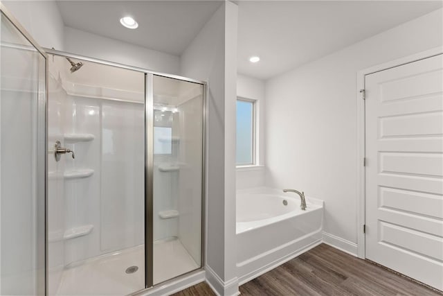bathroom featuring wood finished floors, recessed lighting, a stall shower, baseboards, and a bath