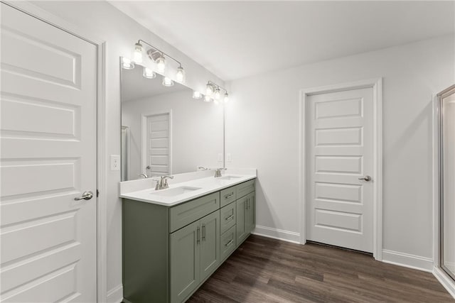 full bathroom featuring double vanity, wood finished floors, baseboards, and a sink