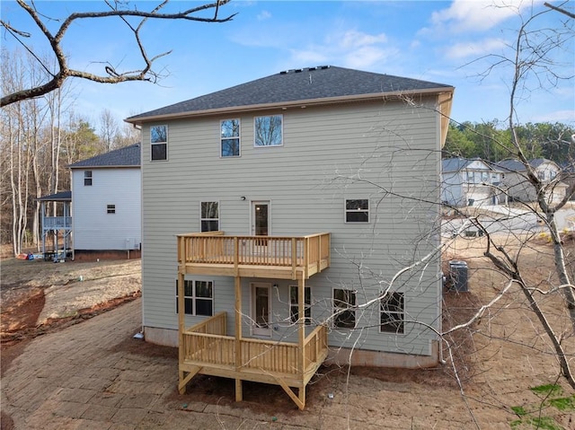 back of house with a wooden deck, a shingled roof, and a balcony