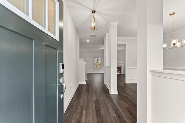 foyer entrance with crown molding, a notable chandelier, baseboards, and dark wood finished floors