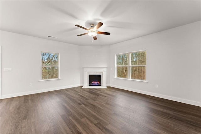 unfurnished living room with plenty of natural light, visible vents, a fireplace, and ceiling fan