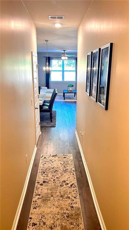 473 Broder Farms Dr, Stockbridge, GA 30281 - hallway featuring dark wood finished floors, baseboards, and a chandelier