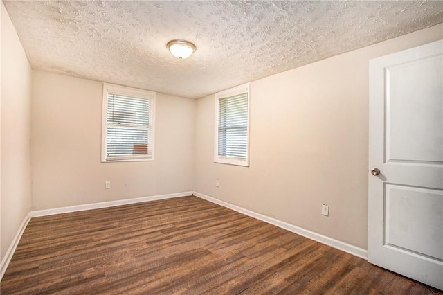 spare room with a textured ceiling and dark hardwood / wood-style floors