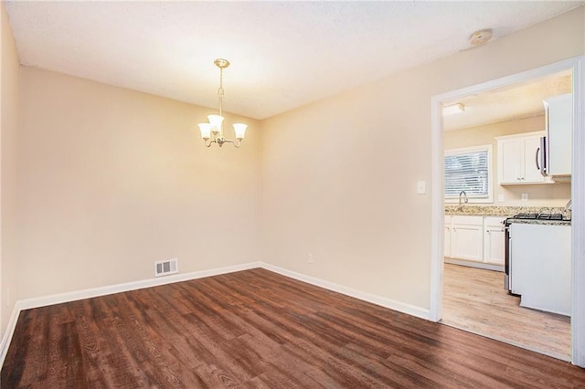 unfurnished dining area featuring a chandelier, wood-type flooring, and sink