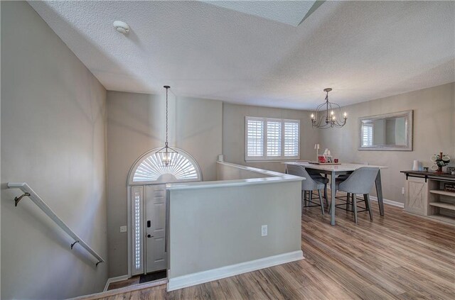 entrance foyer featuring light hardwood / wood-style flooring, a textured ceiling, and an inviting chandelier