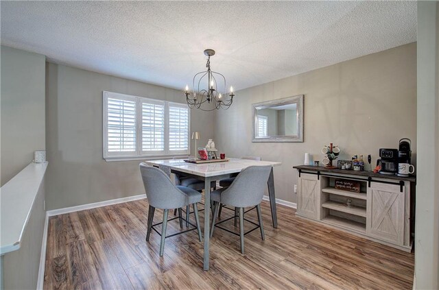 dining space with a textured ceiling, hardwood / wood-style flooring, and an inviting chandelier