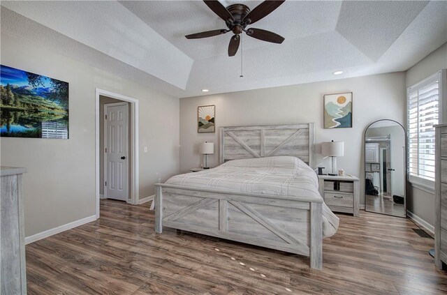 bedroom featuring ceiling fan, dark hardwood / wood-style floors, and a tray ceiling