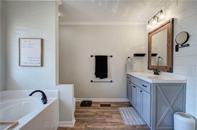 bathroom featuring a textured ceiling, hardwood / wood-style flooring, a bathtub, and ornamental molding