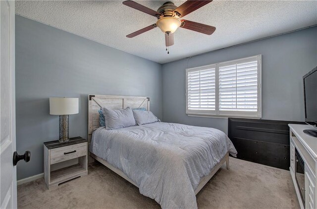 bedroom featuring light carpet, a textured ceiling, and ceiling fan