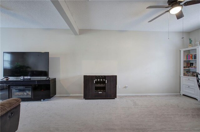 carpeted living room with beamed ceiling, ceiling fan, and a textured ceiling